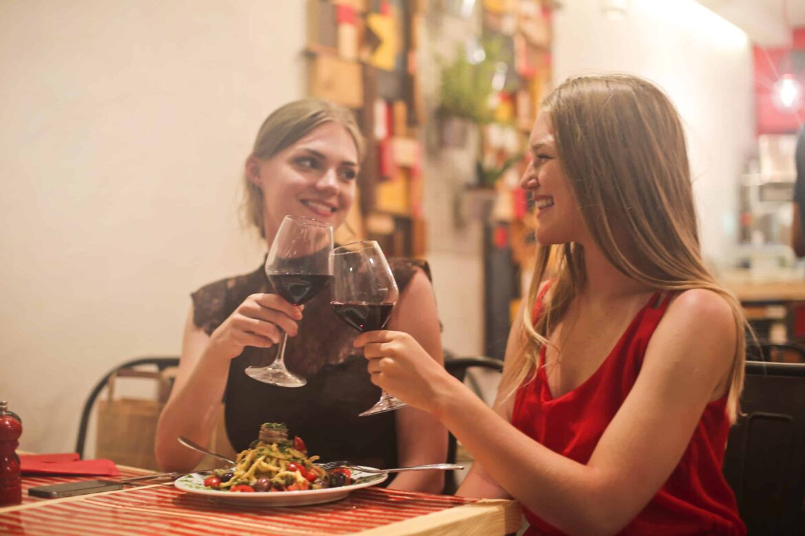 two women holding long stem wine glasses with red liquid stockpack pexels scaled