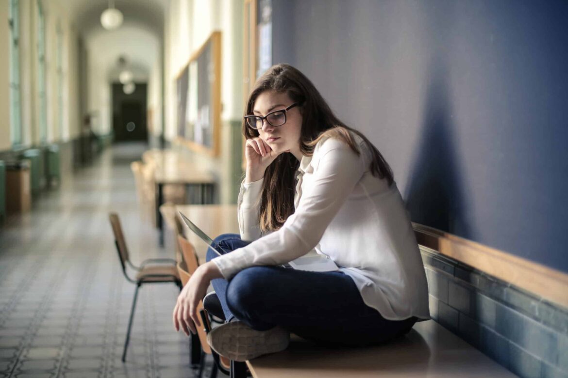 woman in white long sleeve shirt and blue denim jeans sitting on table stockpack pexels scaled