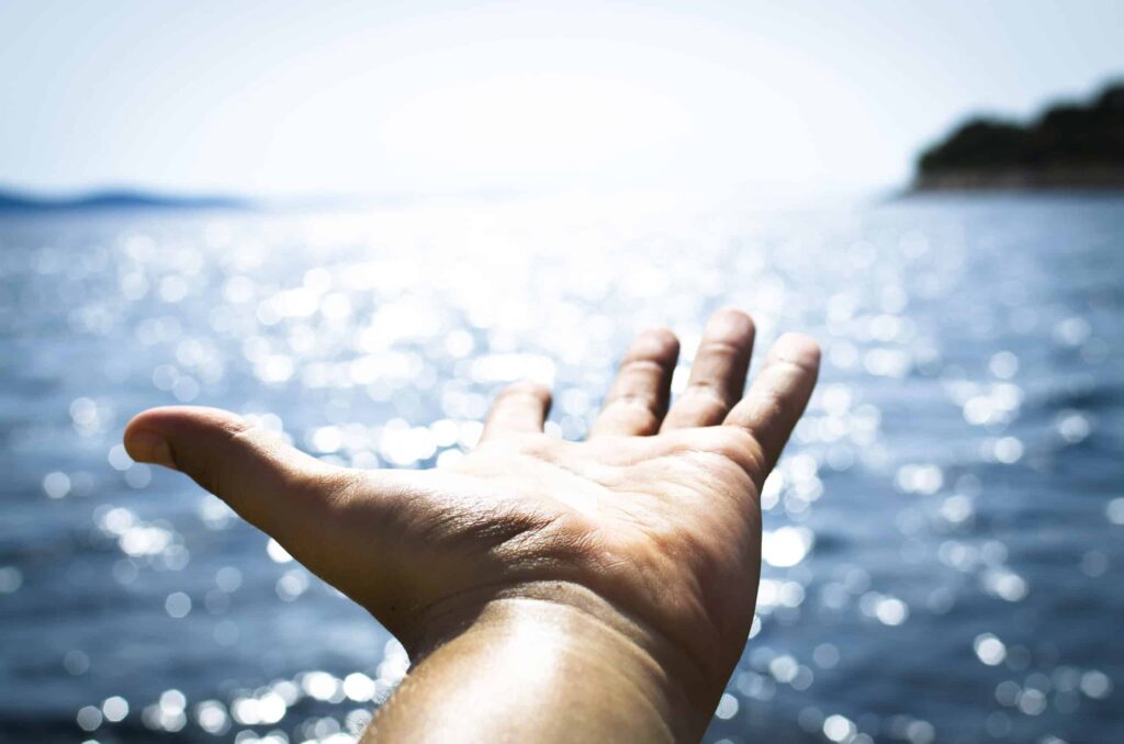 Person hand reaching body of water