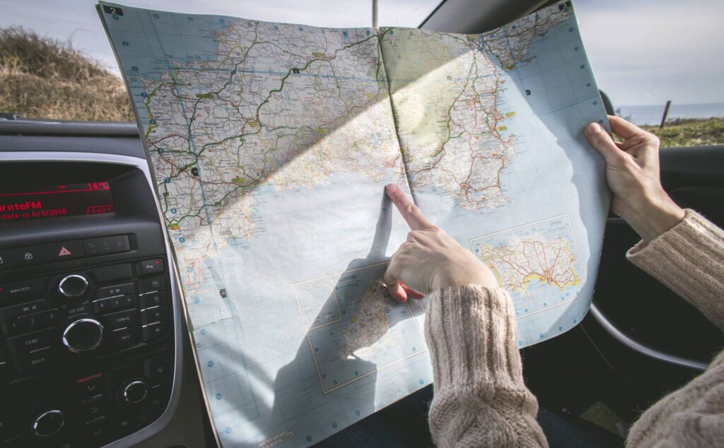 Person wearing beige sweater holding map inside vehicle