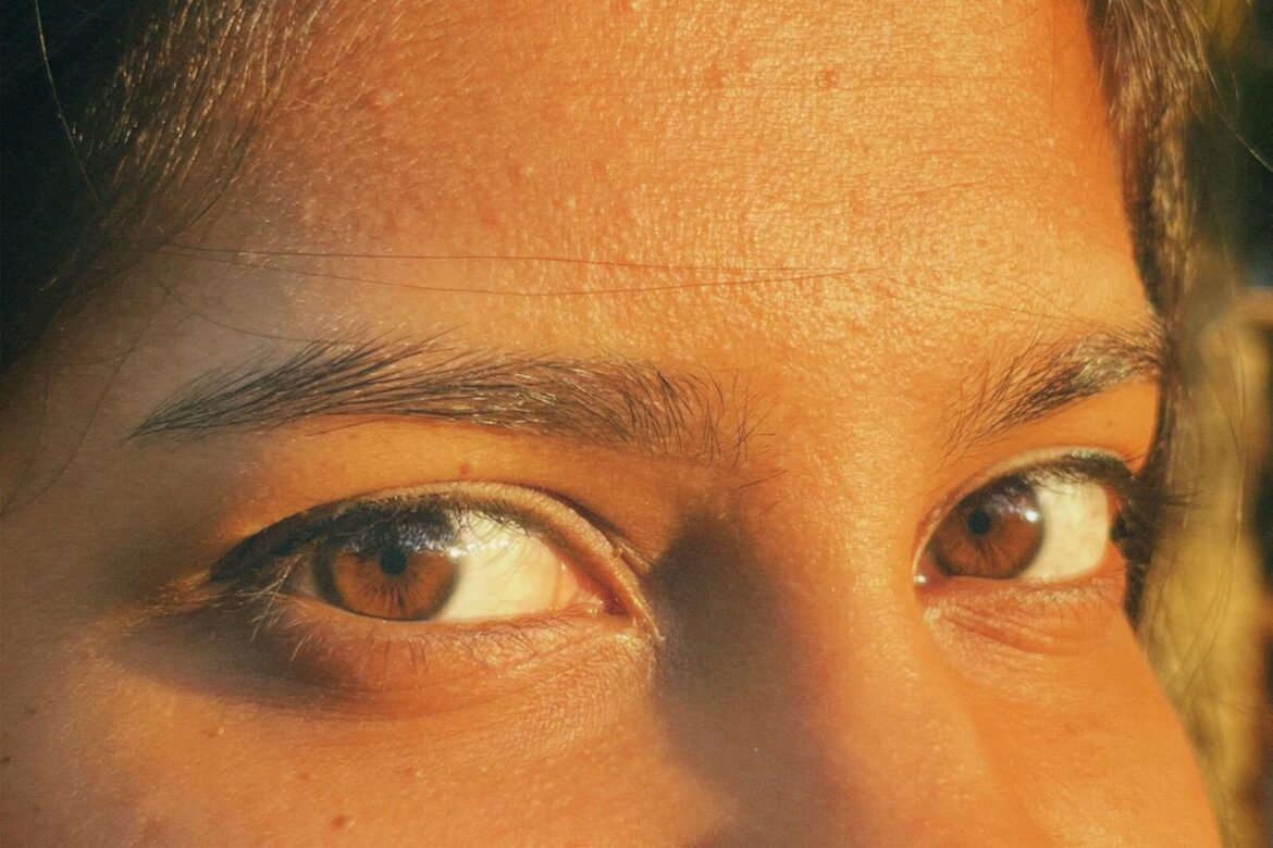 A close-up image highlighting expressive brown eyes with a warm sunlight glow.