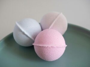 Three vibrant bath bombs displayed on a green ceramic plate, perfect for a spa setting.