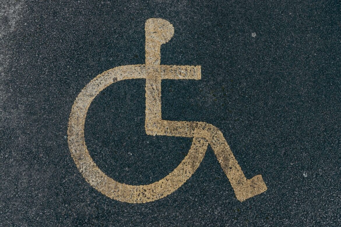 Close-up of a yellow accessibility symbol marked on a dark asphalt surface.