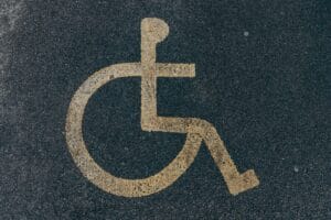 Close-up of a yellow accessibility symbol marked on a dark asphalt surface.