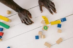 Hands playing with colorful wooden blocks on a white table, sparking creativity and learning.