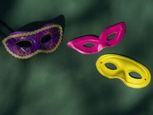 Colorful Venetian masks displayed on a green surface, ready for a masquerade.