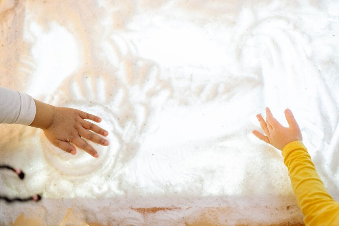 Two children interacting with a textured illuminated surface, engaging sensory play.