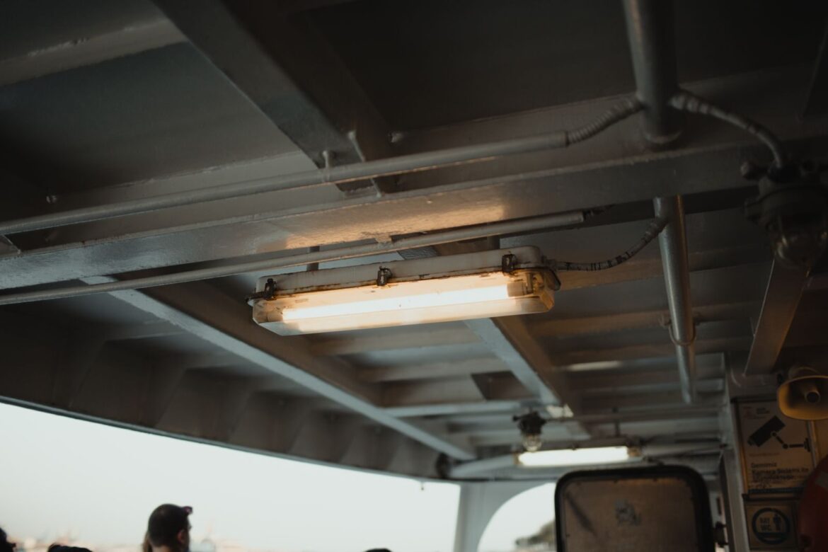 Ceiling view aboard an Istanbul ferry showcasing industrial lighting and a glimpse of passengers.