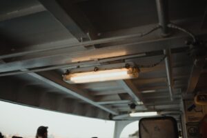 Ceiling view aboard an Istanbul ferry showcasing industrial lighting and a glimpse of passengers.